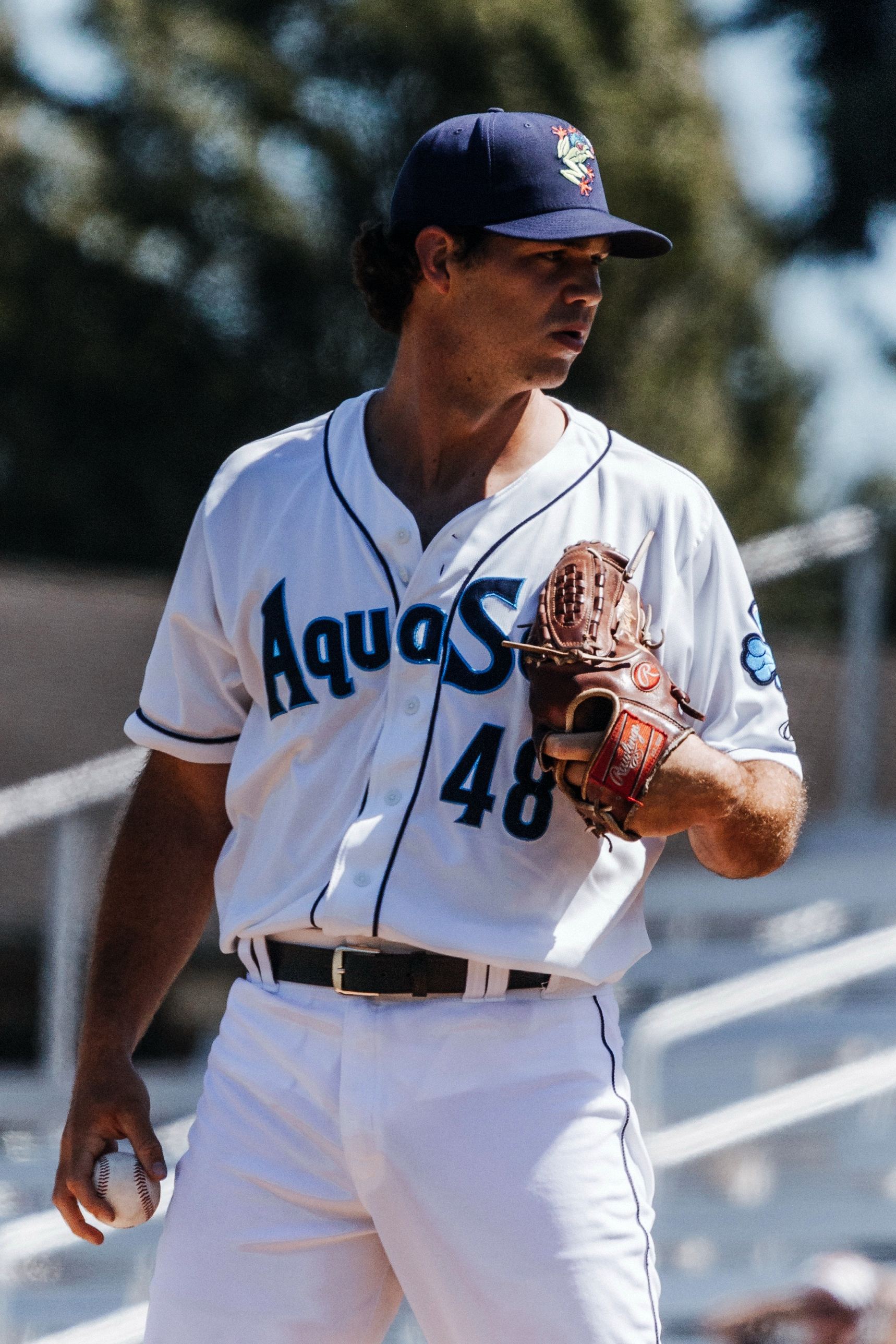 Jarod Bayless in his white AquaSox jersey, glove at his chest, looking off to the side